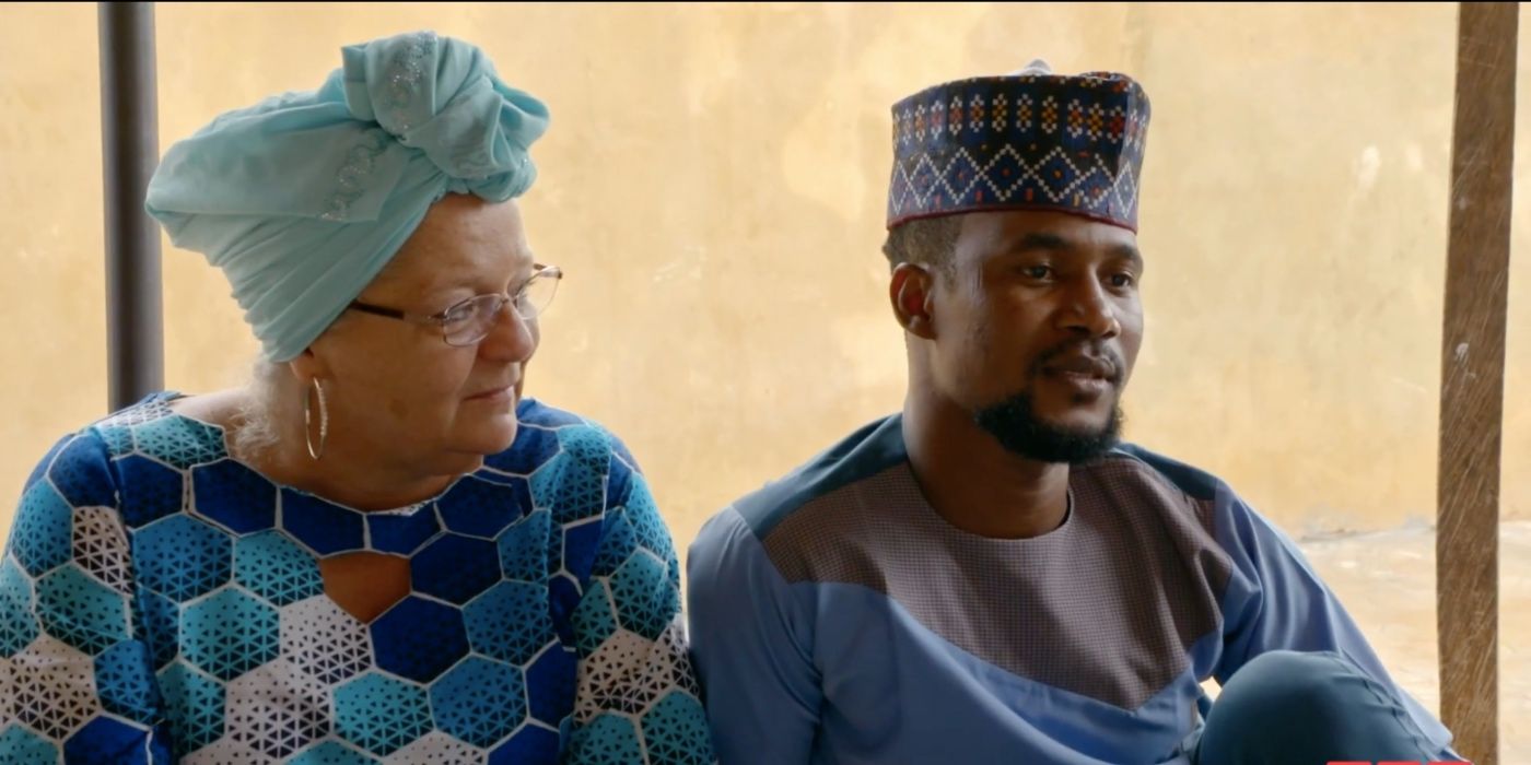 Lisa looking at Usman from 90 Day Fiance wearing traditional Nigerian clothes and looking serious.