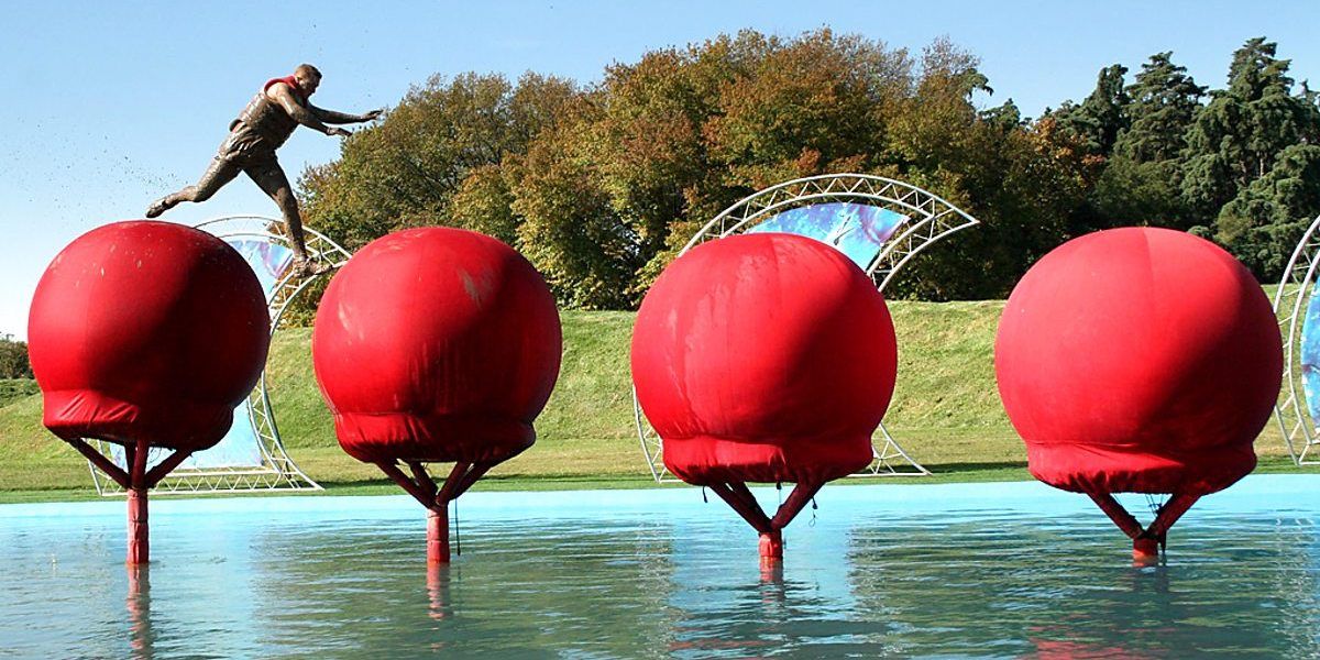A contestant runs across the red balls in Wipeout