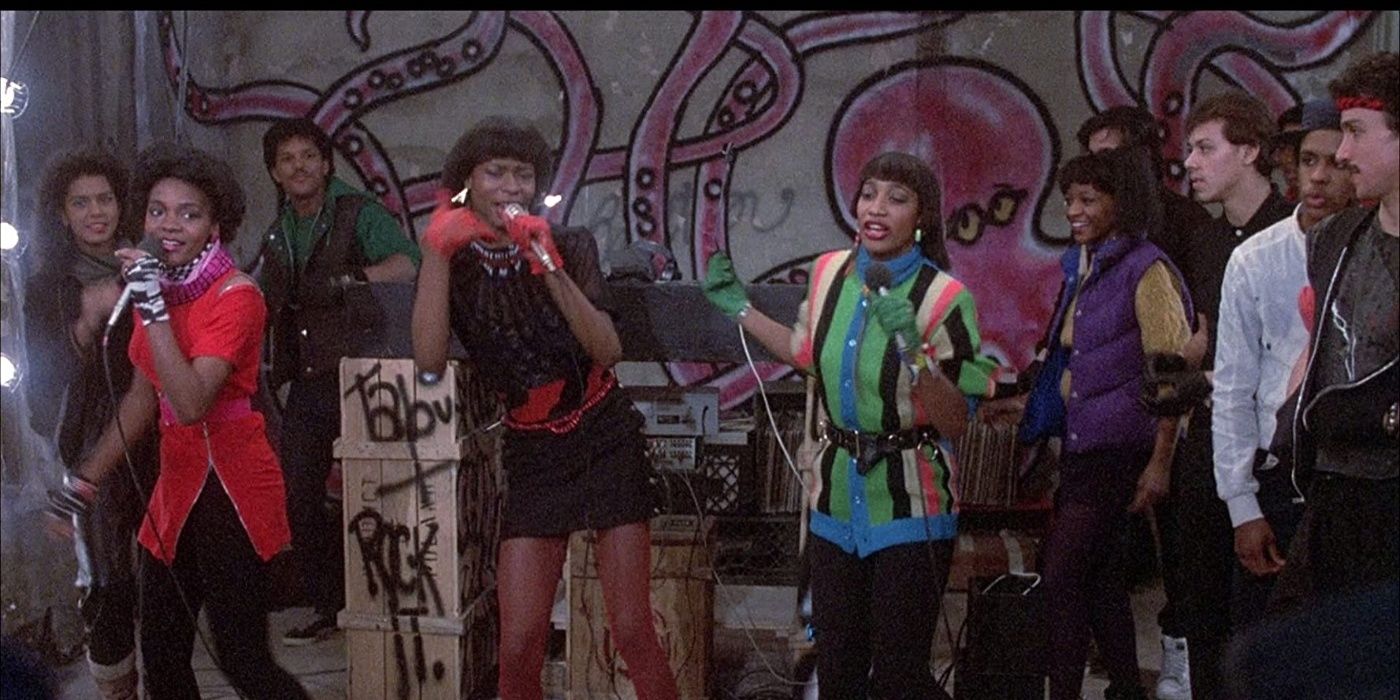 A trio of MCs performing in front of a group in a still from Beat Street