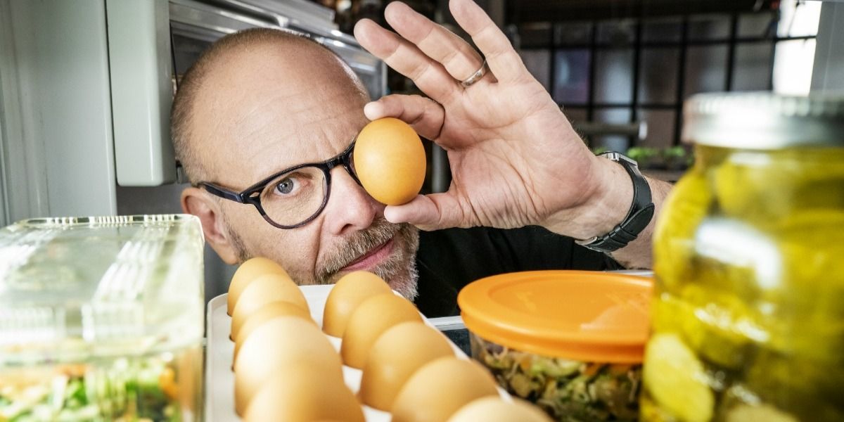Alton Brown looking into a fridge full of food on Good Eats