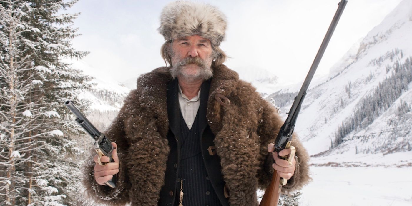 John Hurt holding two guns under the snow in The Hateful Eight