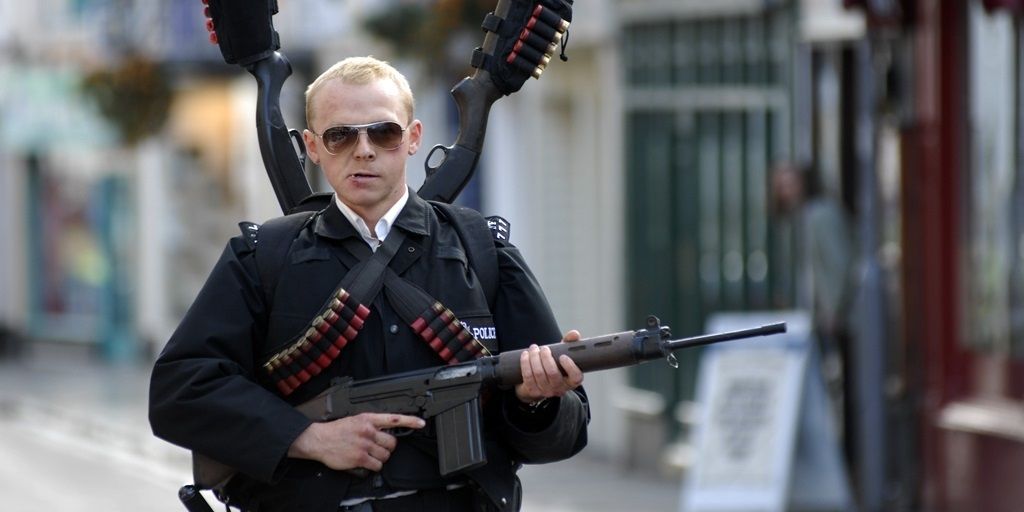 Simon Pegg as Nicholas Angel walking the streets carrying many weapons for the final showdown