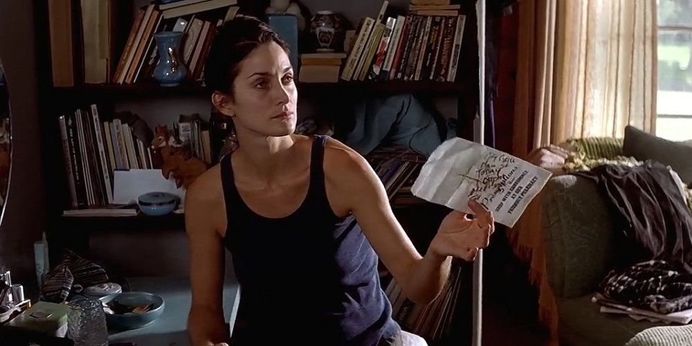 Natalie offering a piece of paper to someone in Memento.
