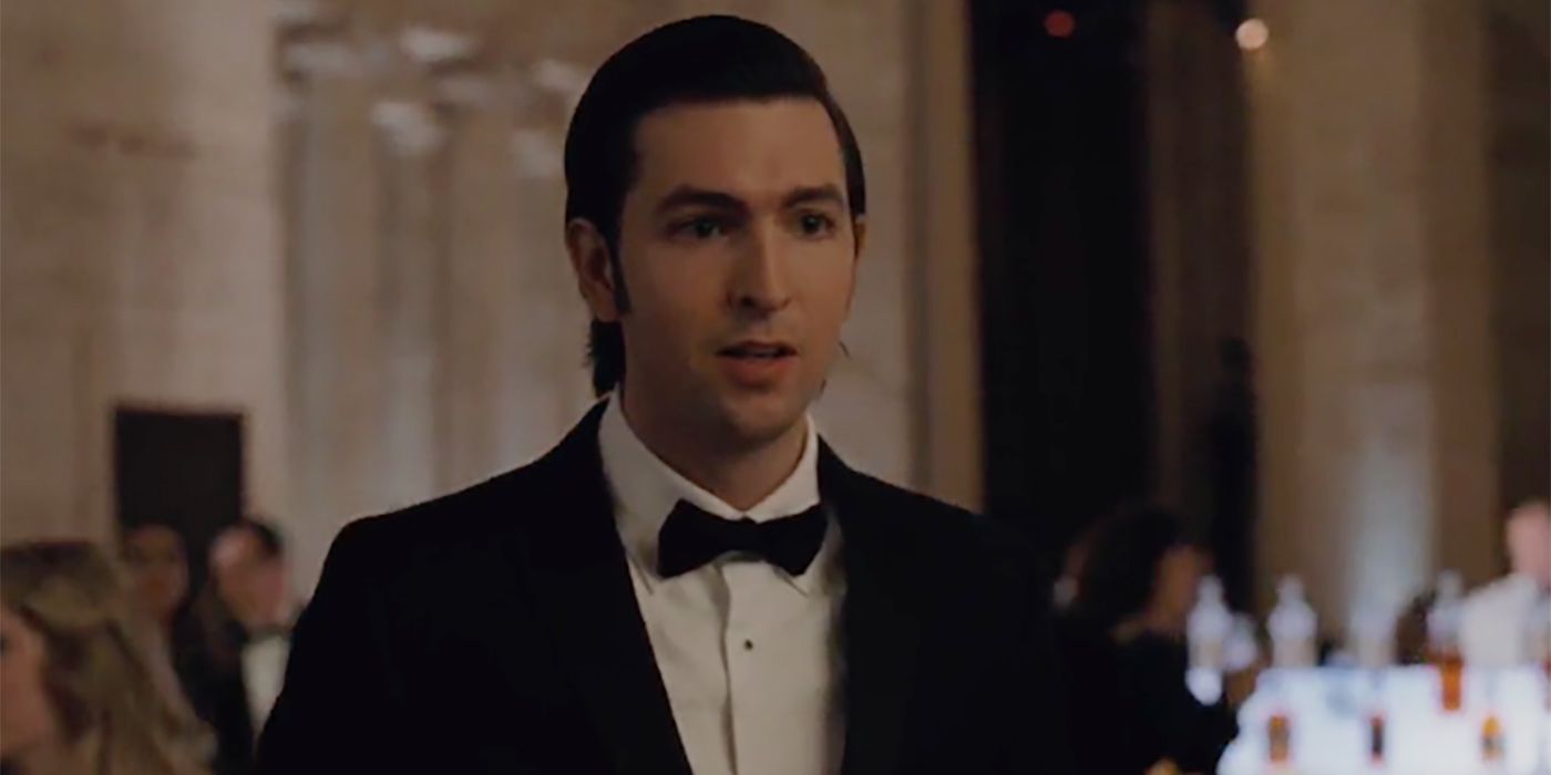 Greg standing in a suit and bowtie with his hair slicked back at a gala event in Succession
