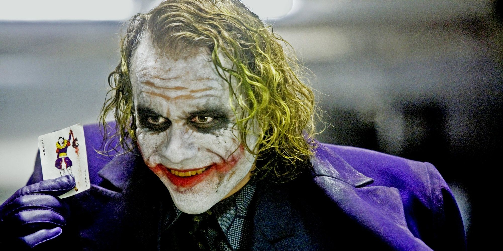 The Joker holding up a playing card
