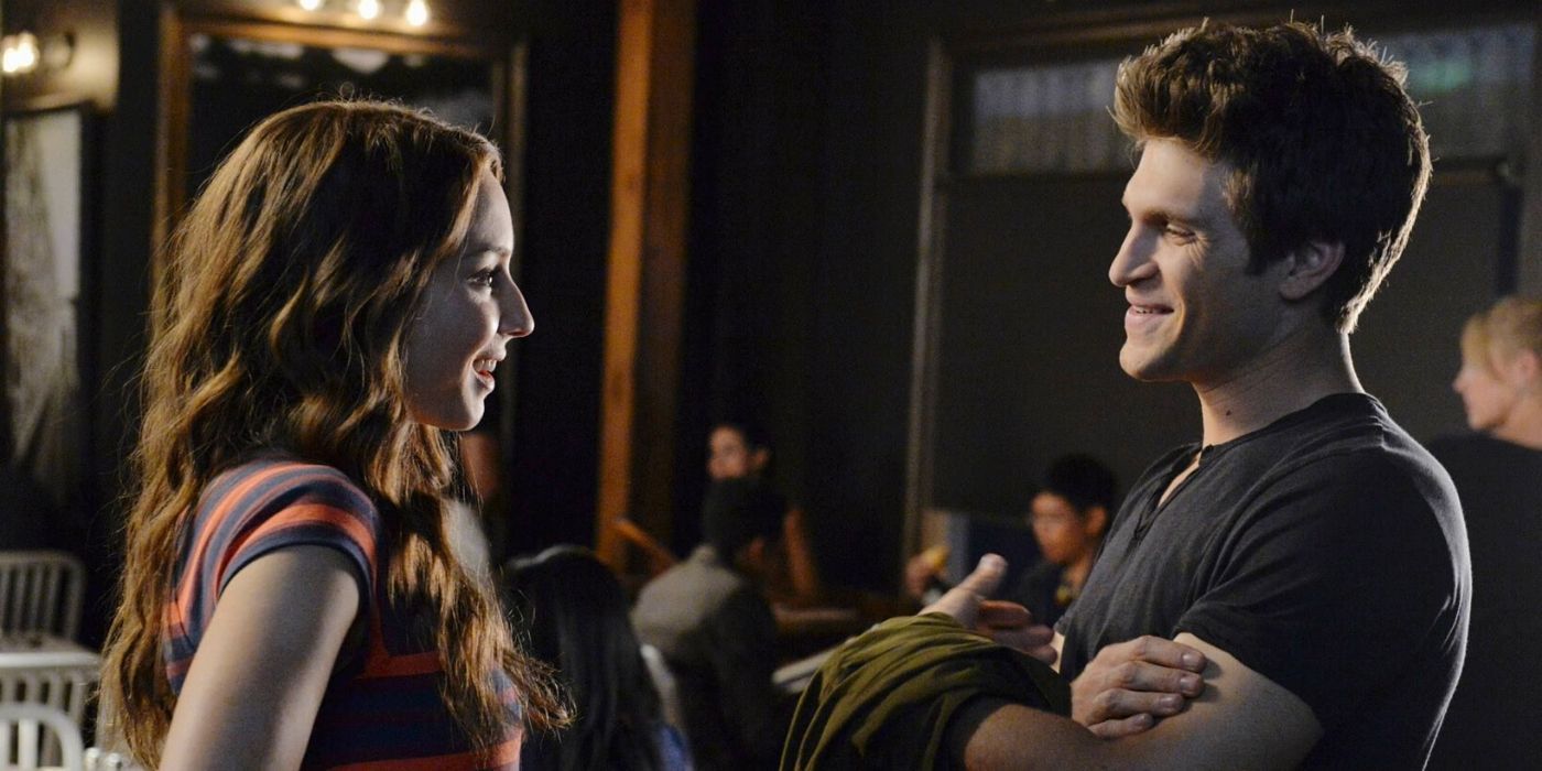 Spencer e Toby conversando e sorrindo em um restaurante em Pretty Little Liars