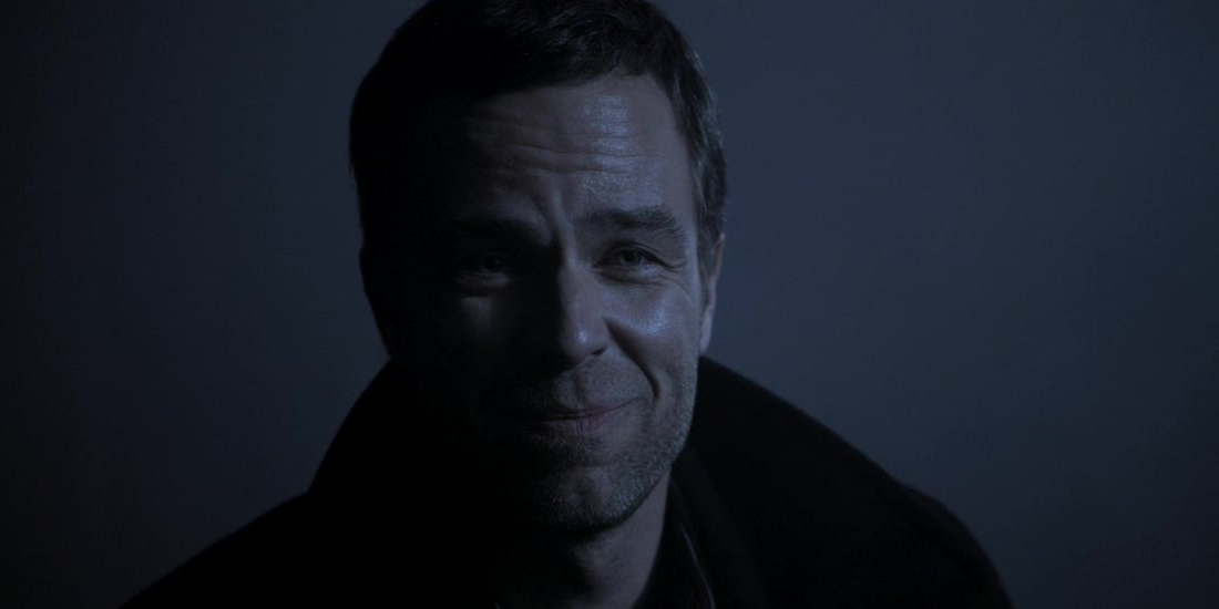 Chris Argent smiles in the shadows in Teen Wolf