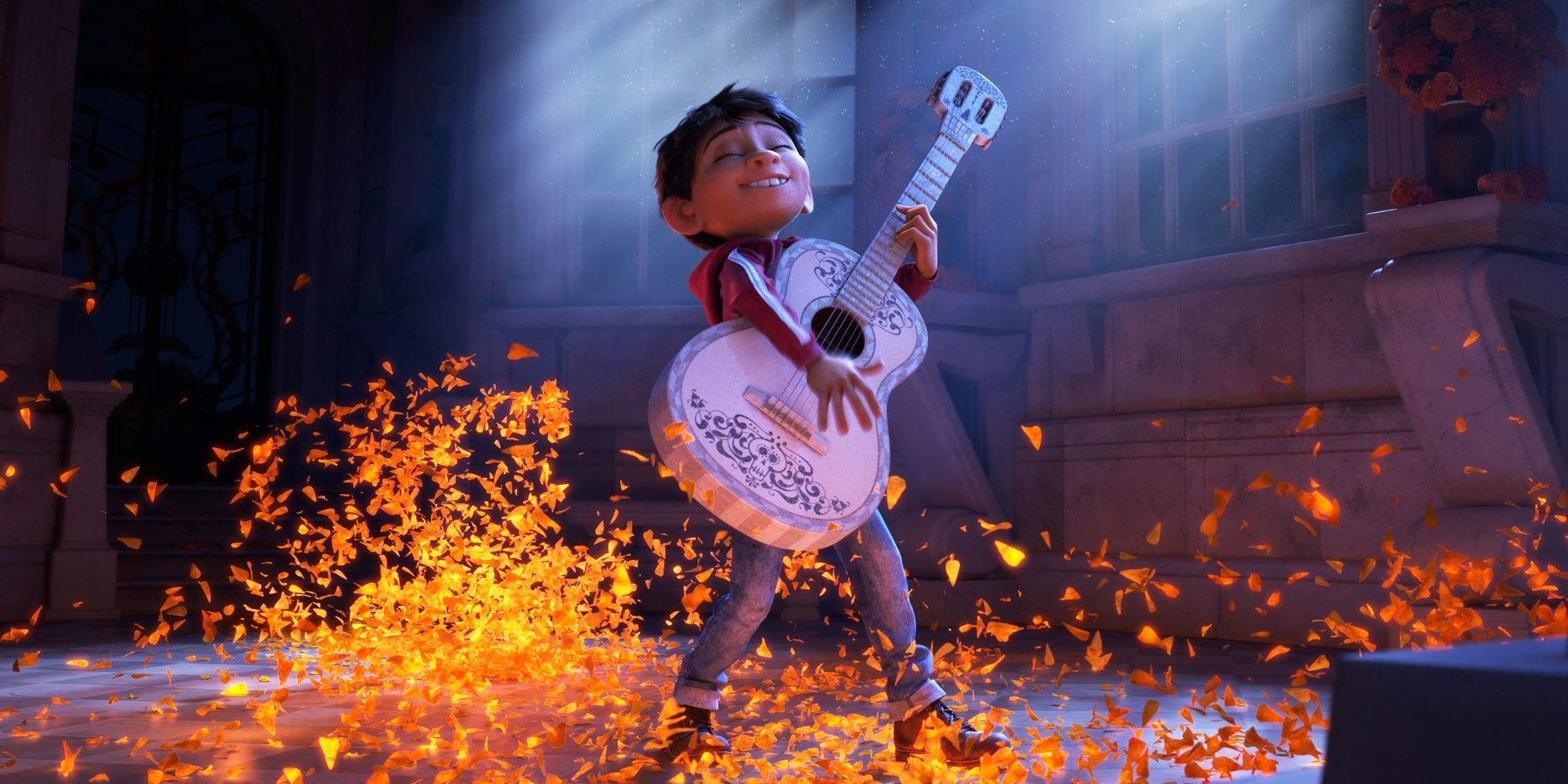 Miguel strums the guitar strings as leaves rise around him in Coco.