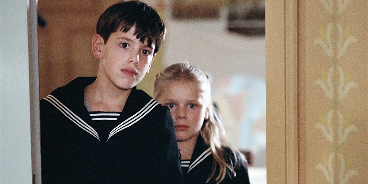 Dois irmãos parados na porta em Fanny And Alexander.