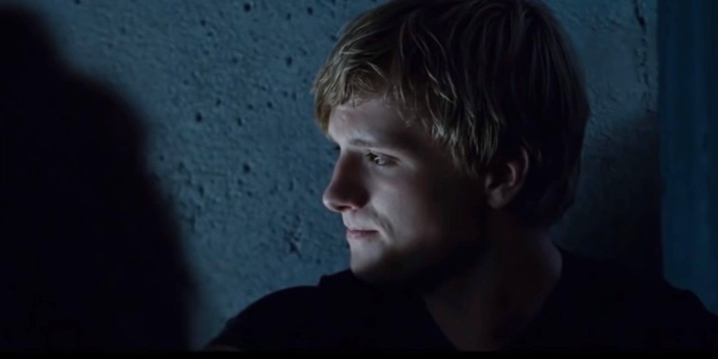 Peeta sits against the wall in shadow in Hunger Games