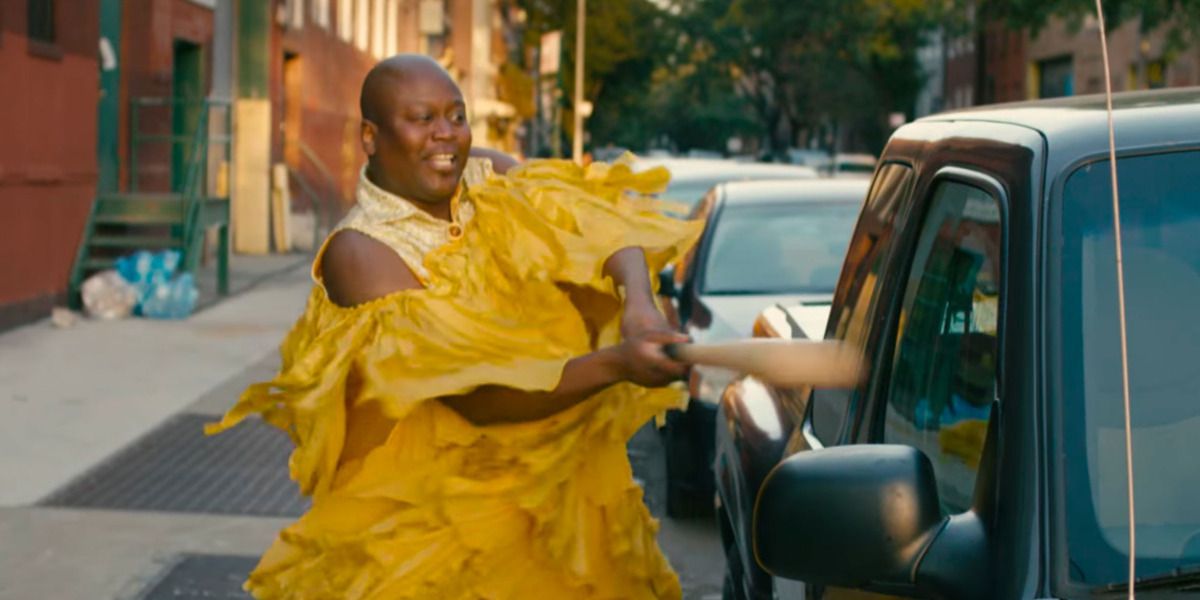 Titus in yellow dress smashing car with baseball bat