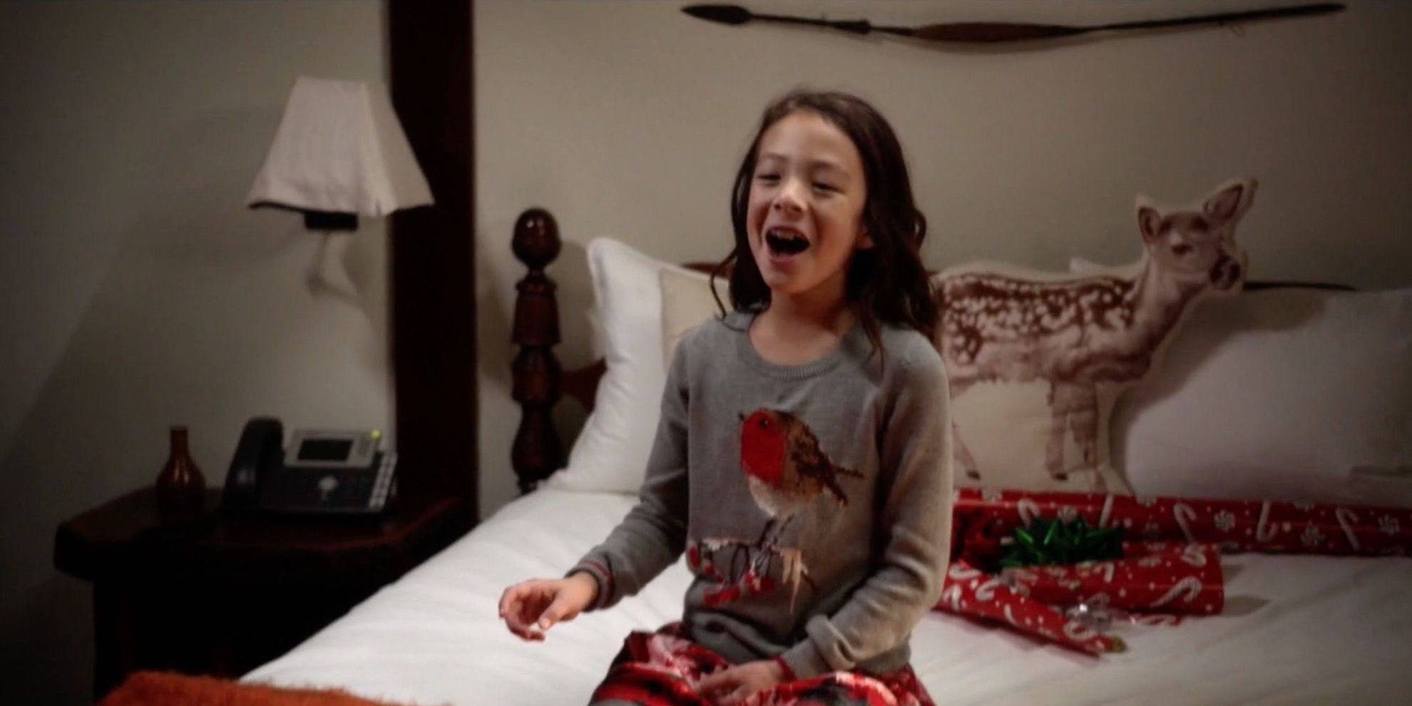 Lily kneeling on the bed and smiling in Modern Family