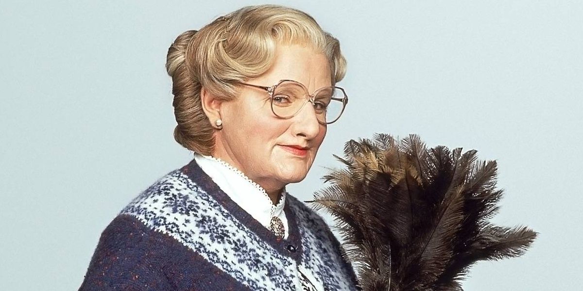 Mrs Doubtfire smiling while holding a duster