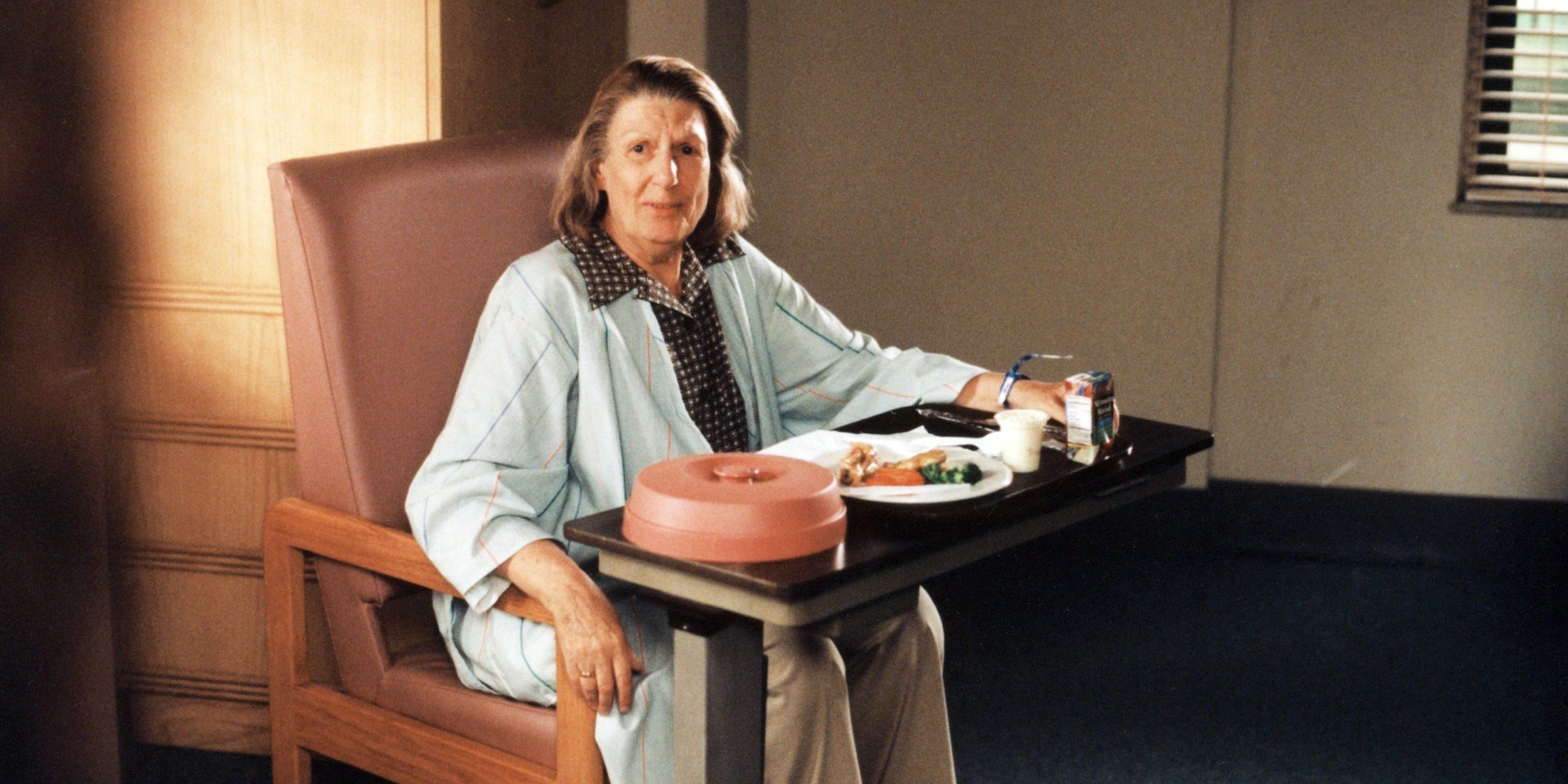 Livia Soprano sits in front of a table with food