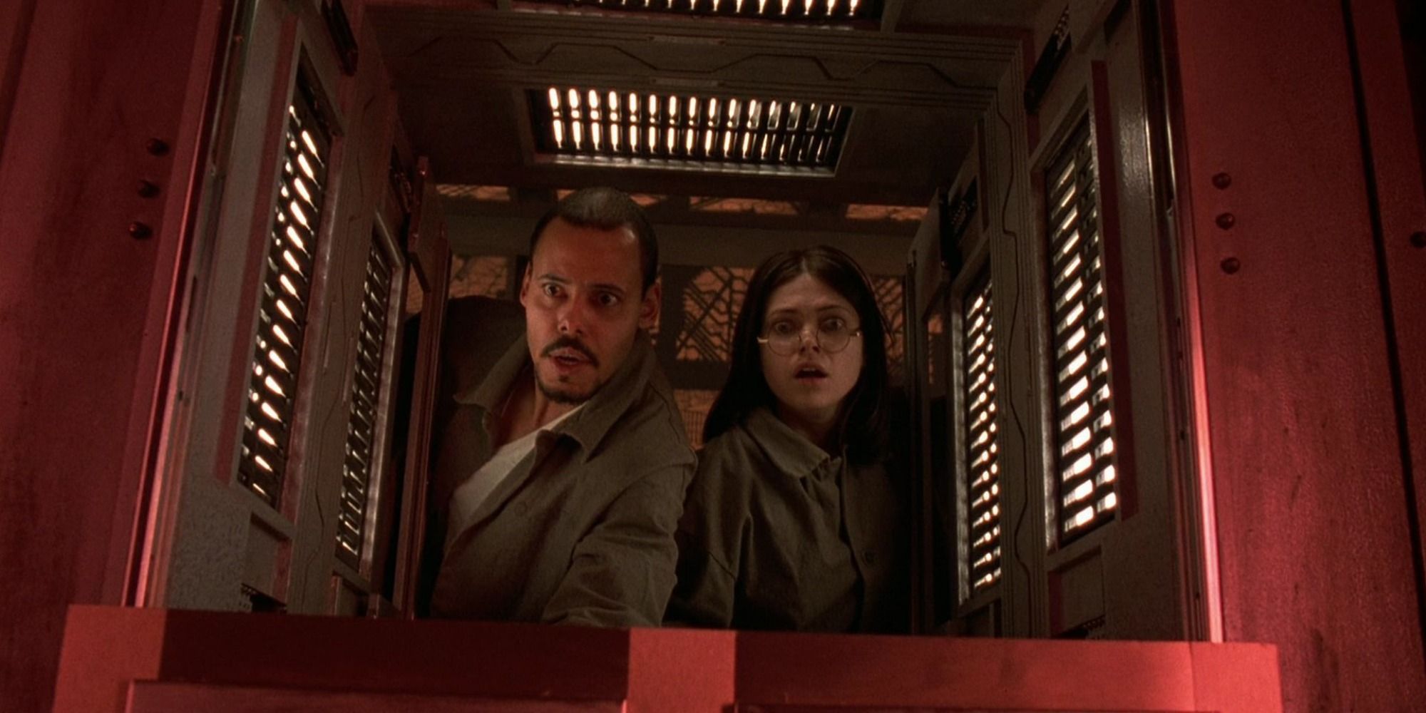 Quentin and Joan looking horror through a hatch in Cube (1997)