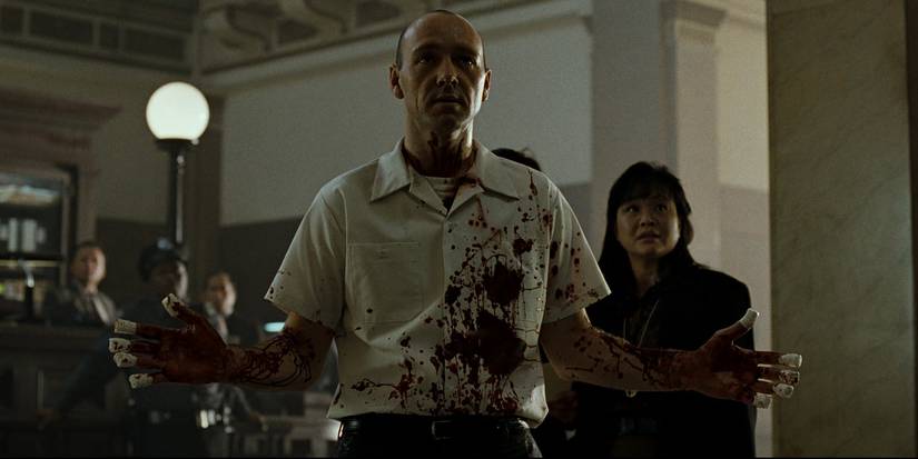 A bloodied John Doe raises his hands in Se7en