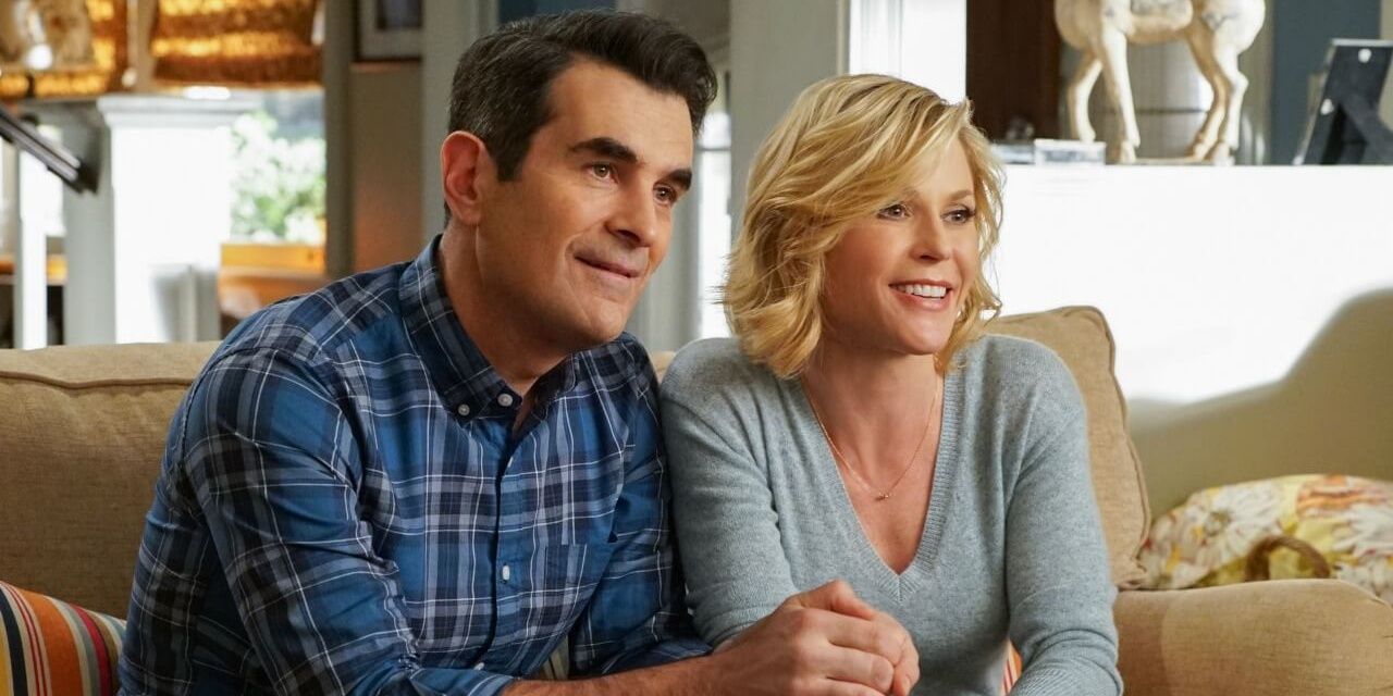 Phil and Claire sitting on the couch and smiling on Modern Family