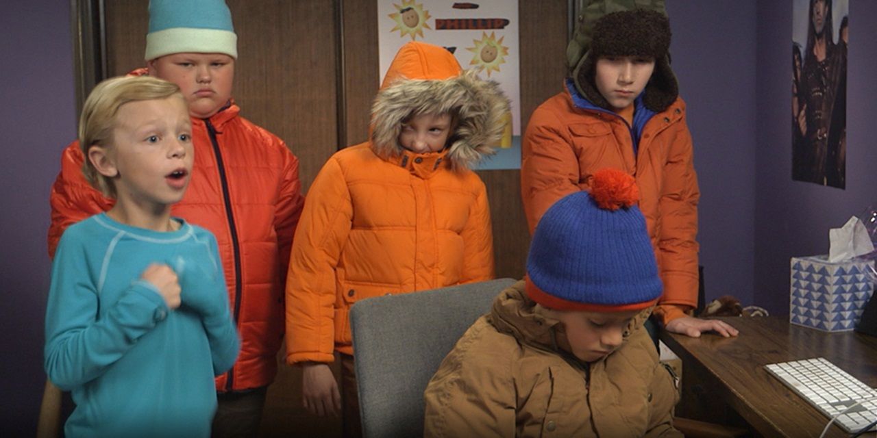 The live-action version of Butters, Kyle, Kenny, Stan, and Cartman in front of a desk in South Park.