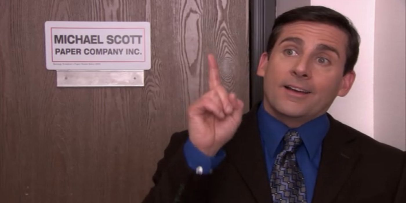 Michael Scott in front of the Michael Scott Paper Company sign.