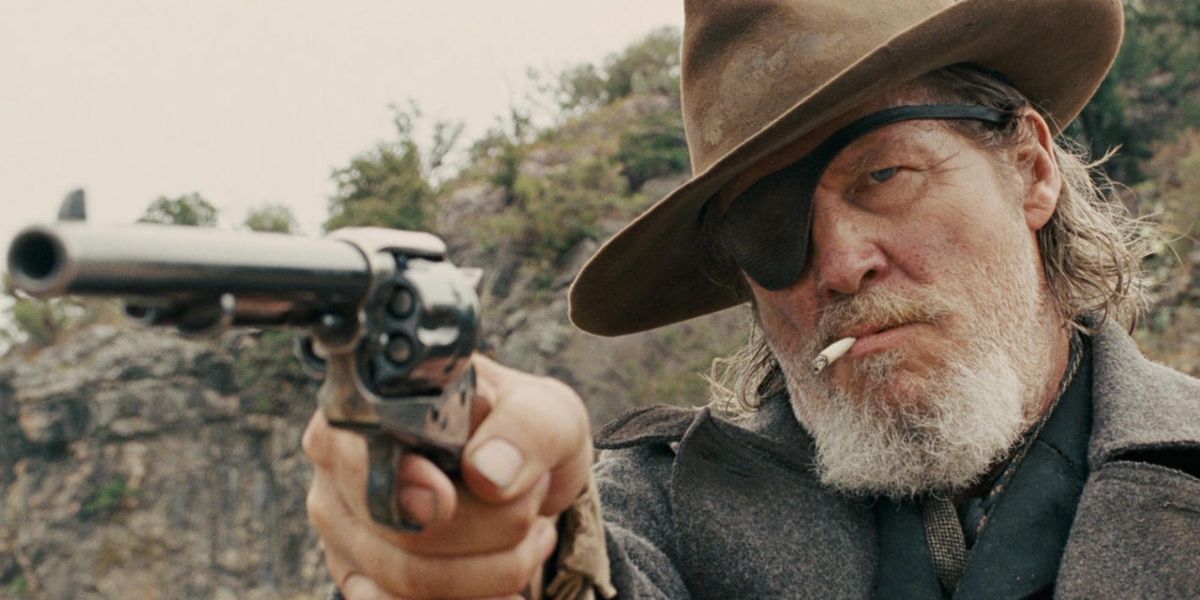 Jeff Bridges smoking a cigarette and pointing a gun in True Grit