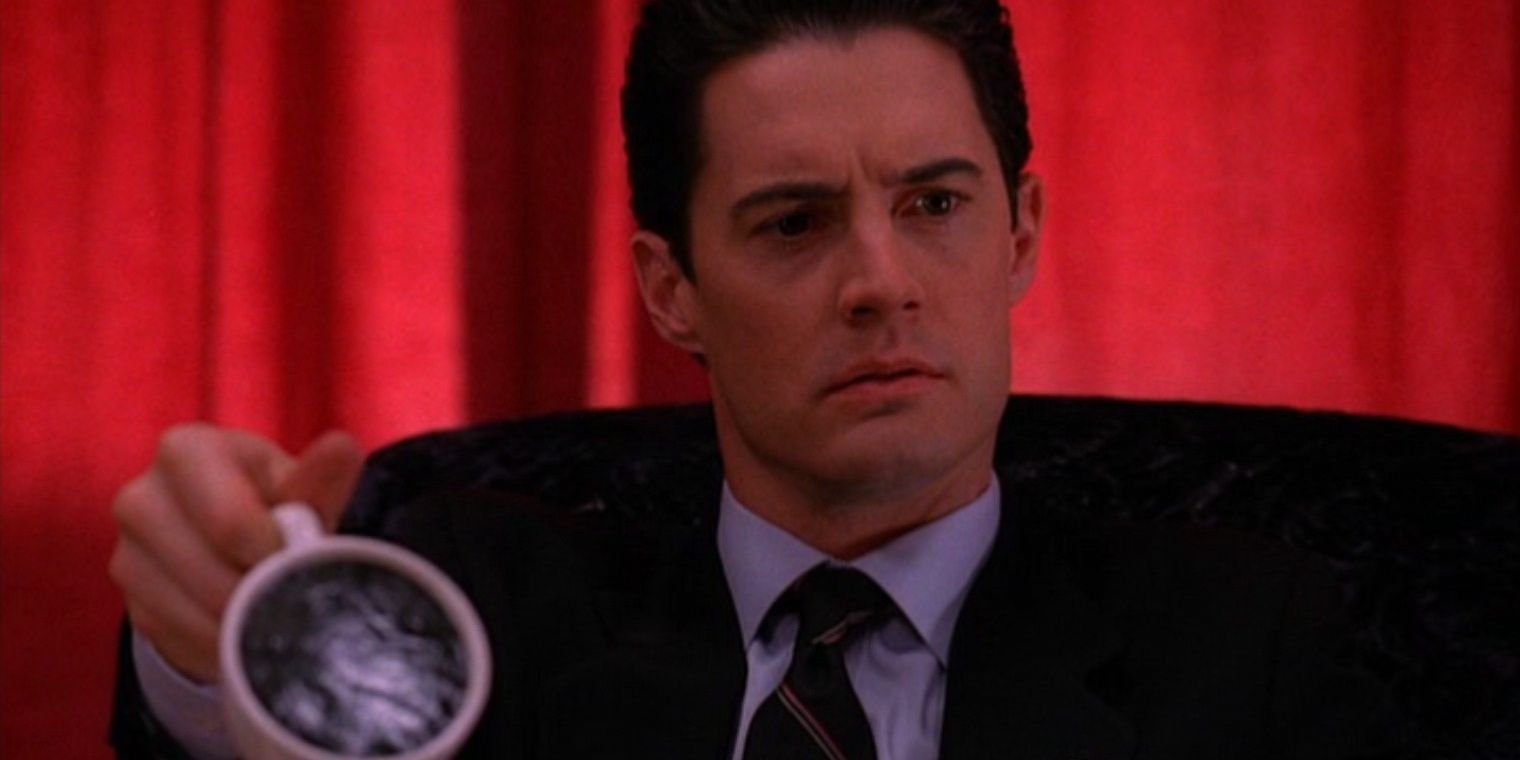 Dale Cooper frowning and holding a cup of coffee in Twin Peaks