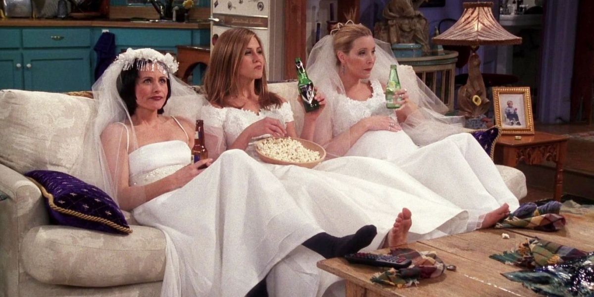 Rachel, Monica and Phoebe in Friends sitting on the sofa in wedding dresses.