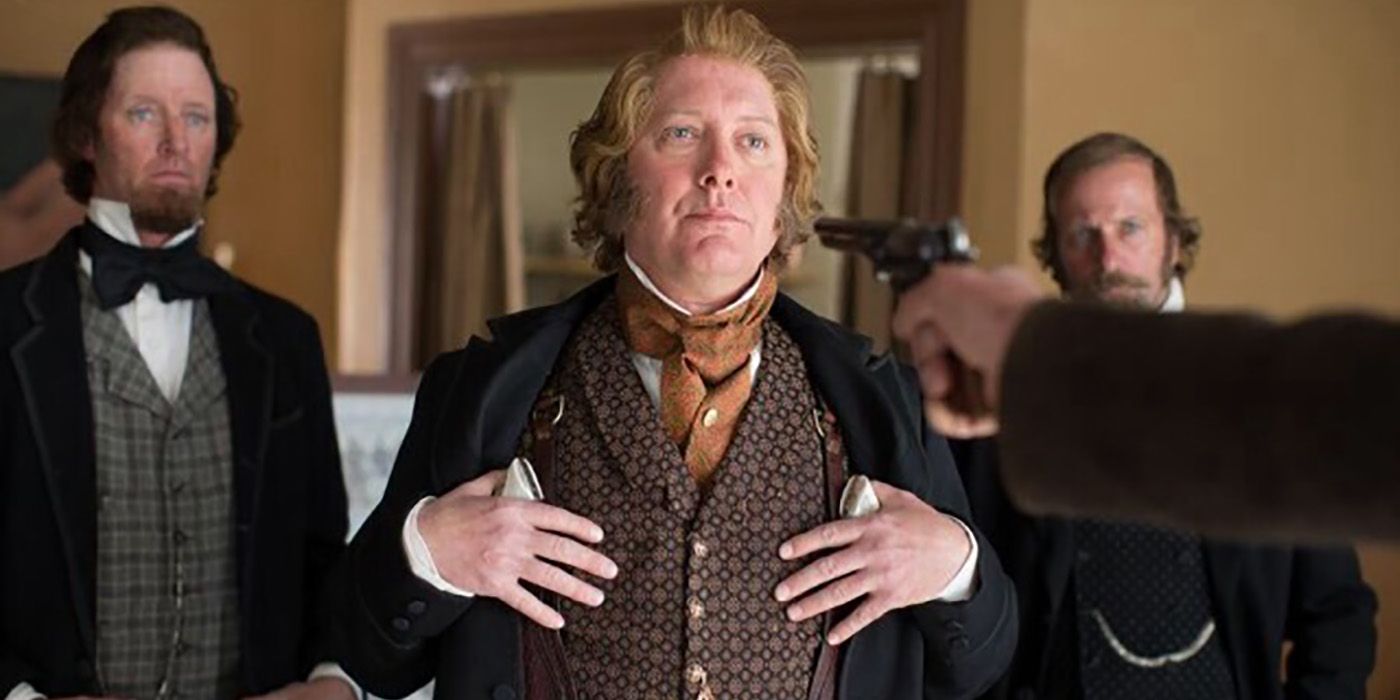 James Spader no período roupas, cabelos ruivos com os dedos nos bolsos do peito em uma cena de The Homesman.