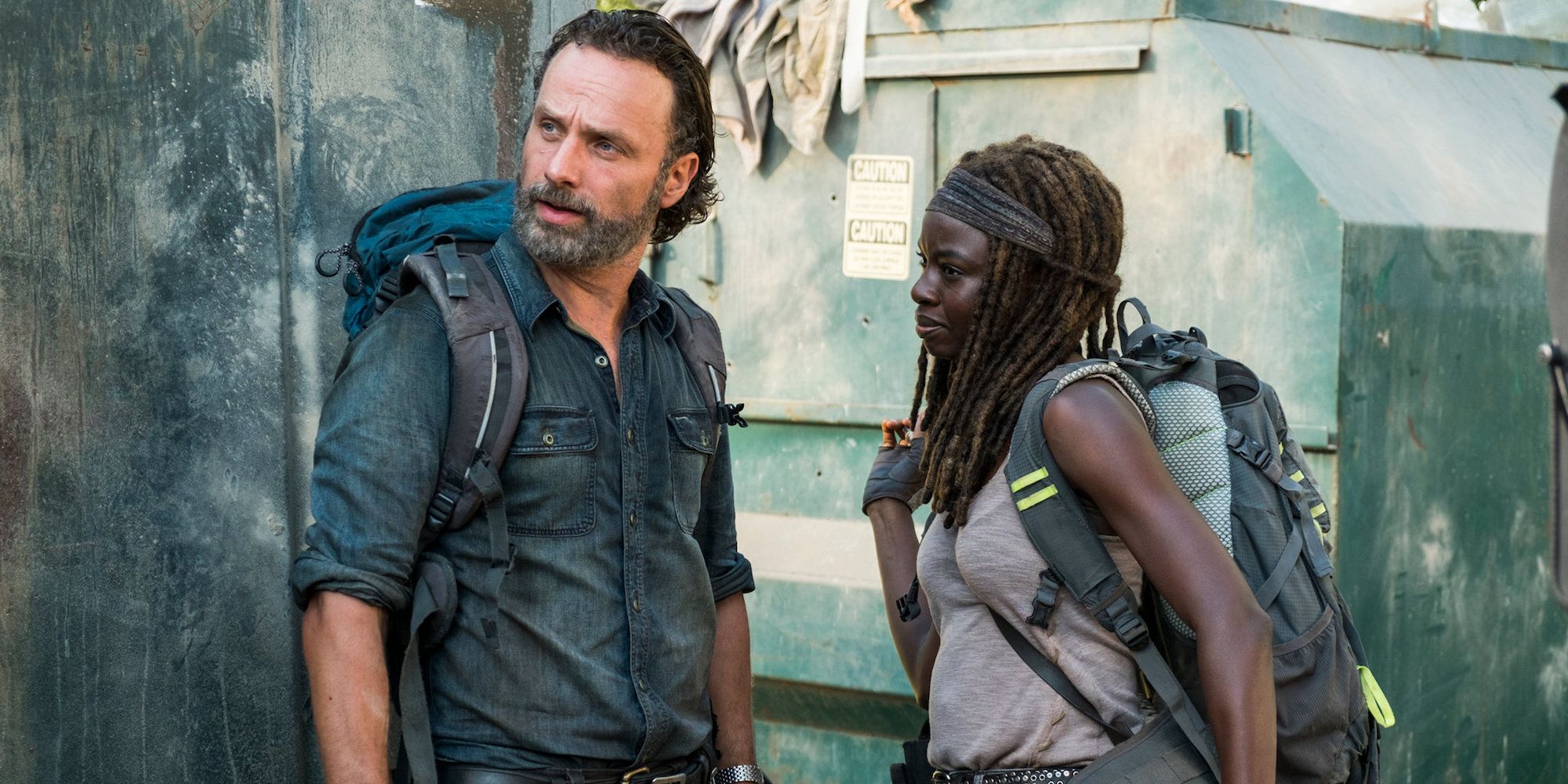 Rick and Michonne standing next to each other with big backpacks on their shoulder