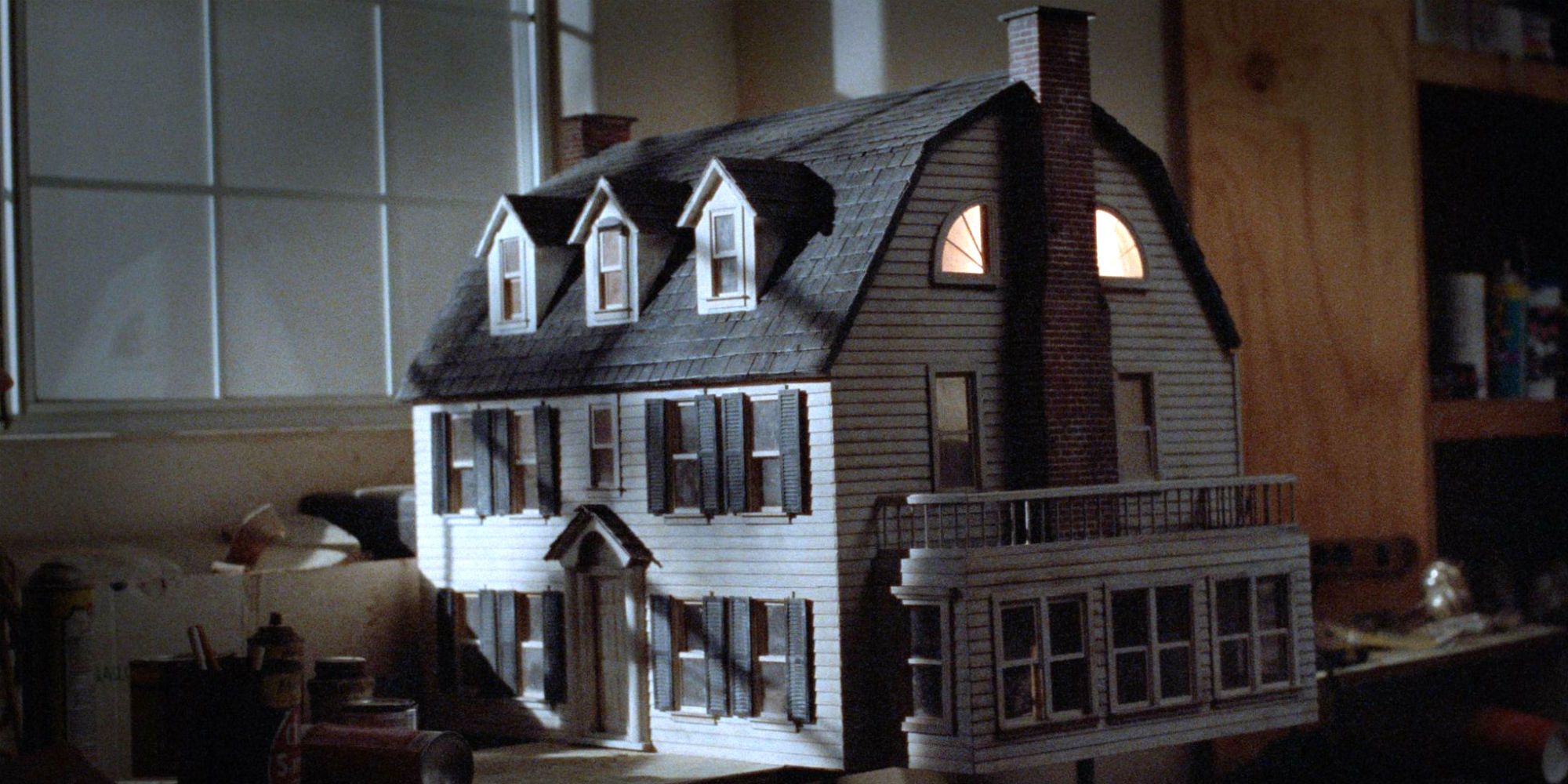Light shines through the upstairs windows of the dollhouse in Amityville Dollhouse