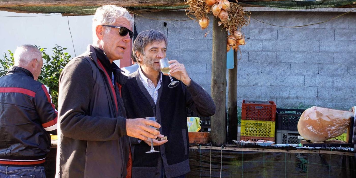 Anthony Bourdain holding a wine glass standing next to someone sipping wine in Parts Unknown.
