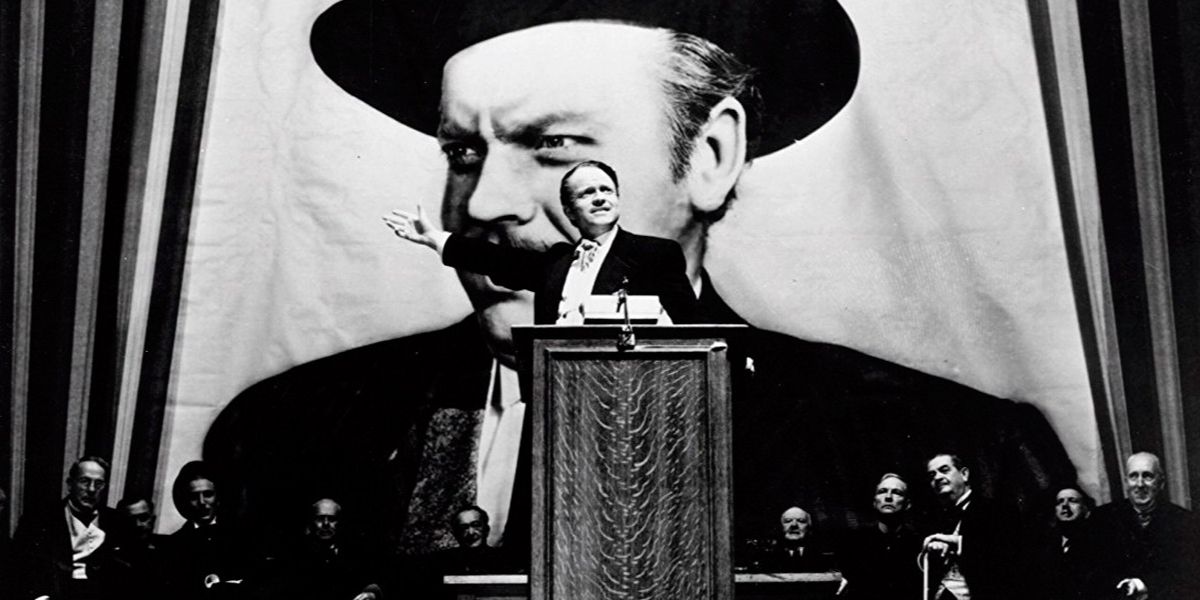 Orson Welles in Citizen Kane giving a speech in front of a campaign poster