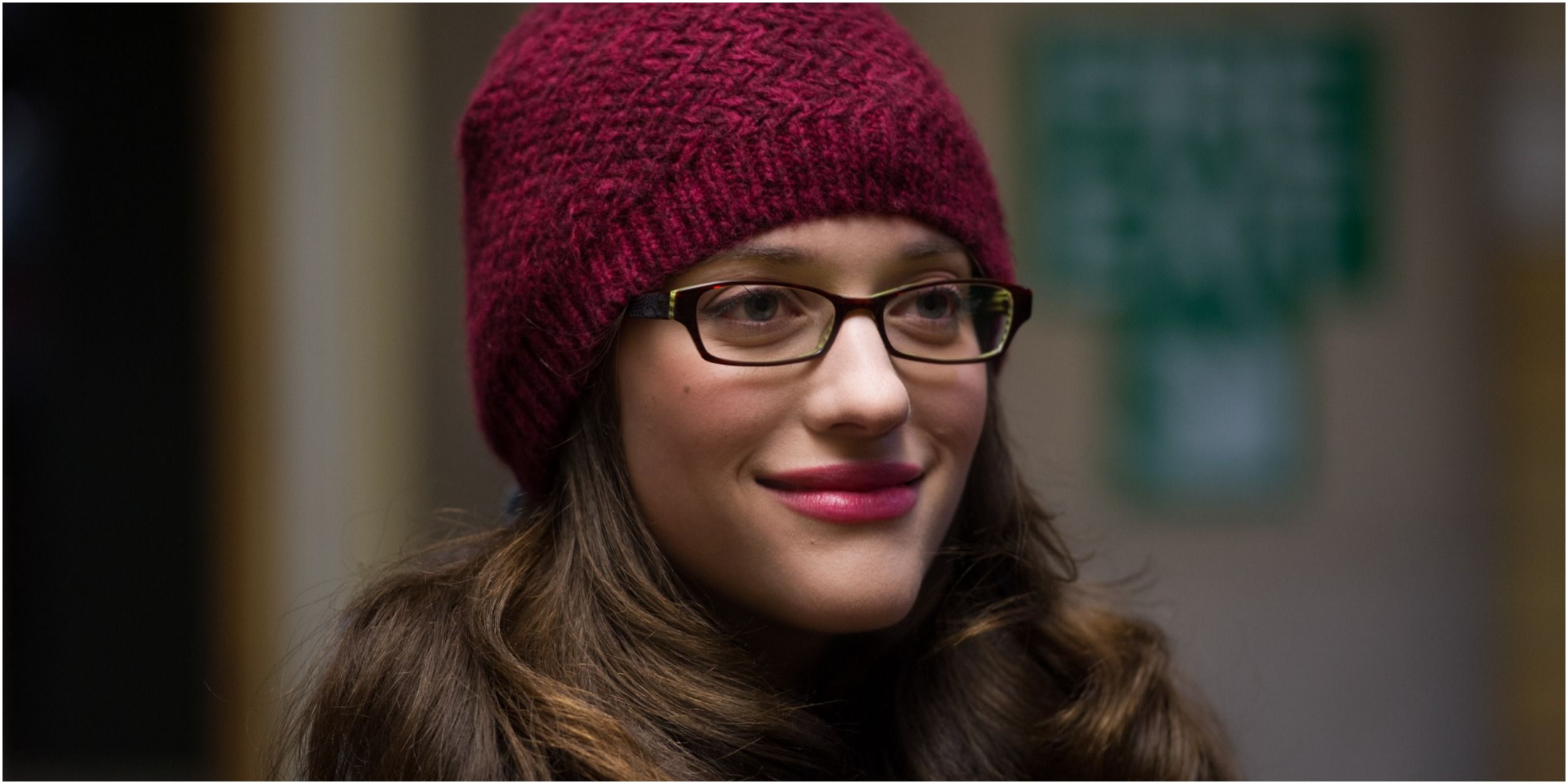 Darcy Lewis in a red hat, smiling, in Thor.