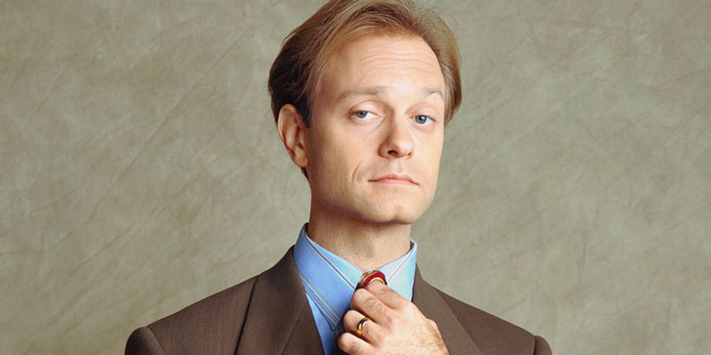 Niles Crane adjusts his tie while looking at the camera in Frasier.