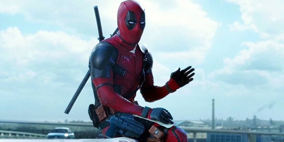 Ryan Reynolds acena com a mão como Deadpool no filme de 2016