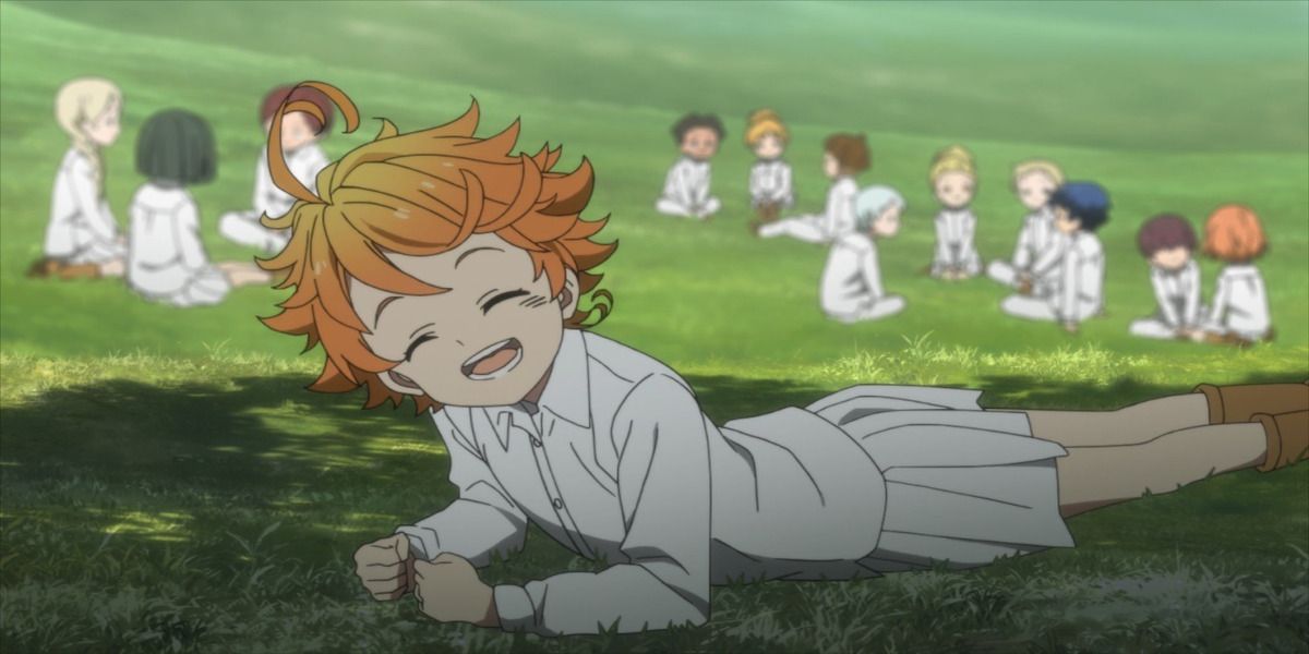 Emma smiles while laying in the grass in The Promised Neverland