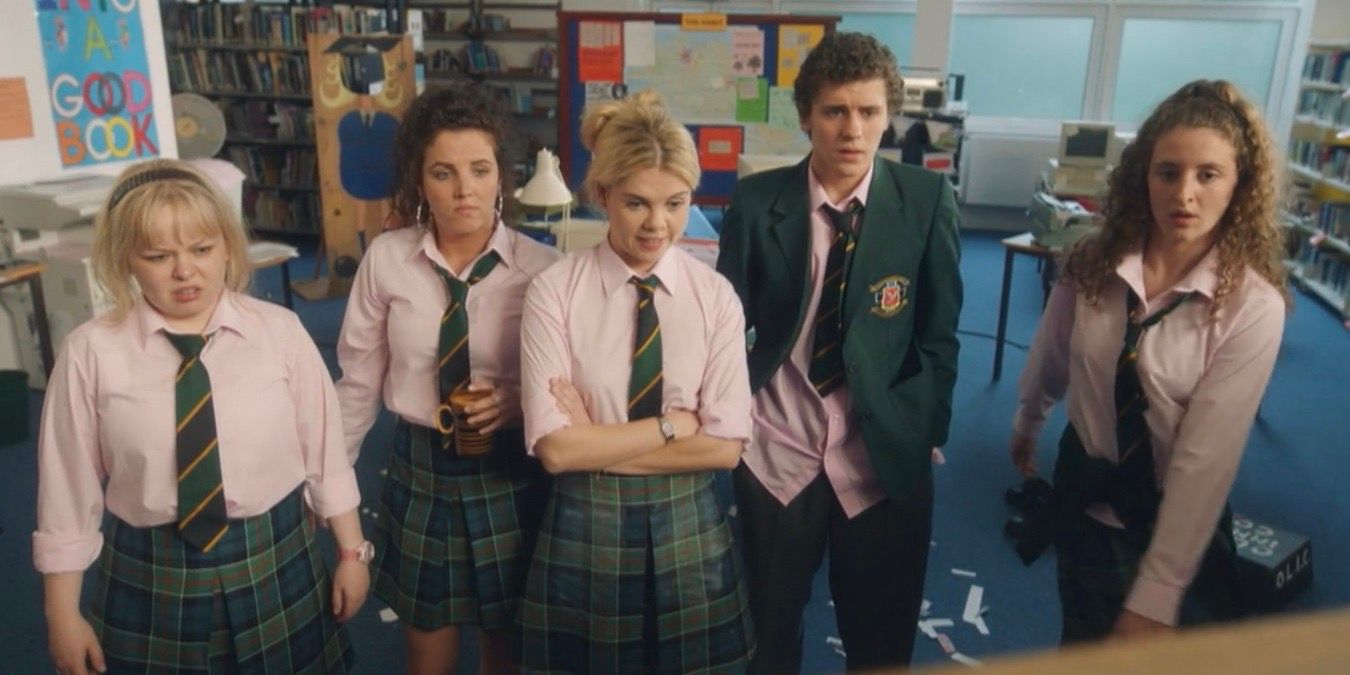 Clare, Michelle, Erin, James, and Orla stand together discussing the school newspaper in Derry Girls