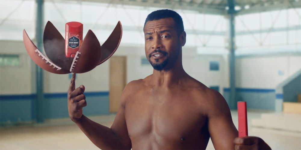 Isaiah Amir Mustafa holding an Old Spice bottle inside a football for an Old Spice commercial