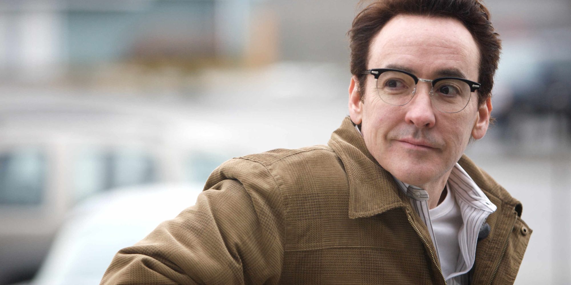 John Cusack wears glasses and smiles in The Frozen Ground.