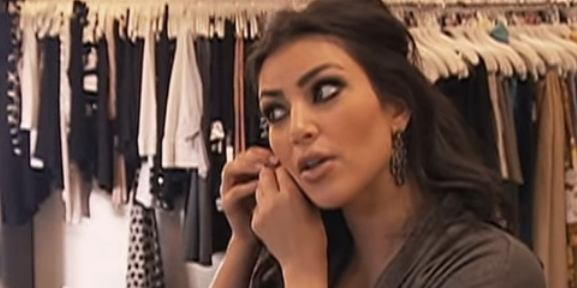 Kim Kardashian putting on earrings in her closet in a scene from Keeping Up with the Kardashians.