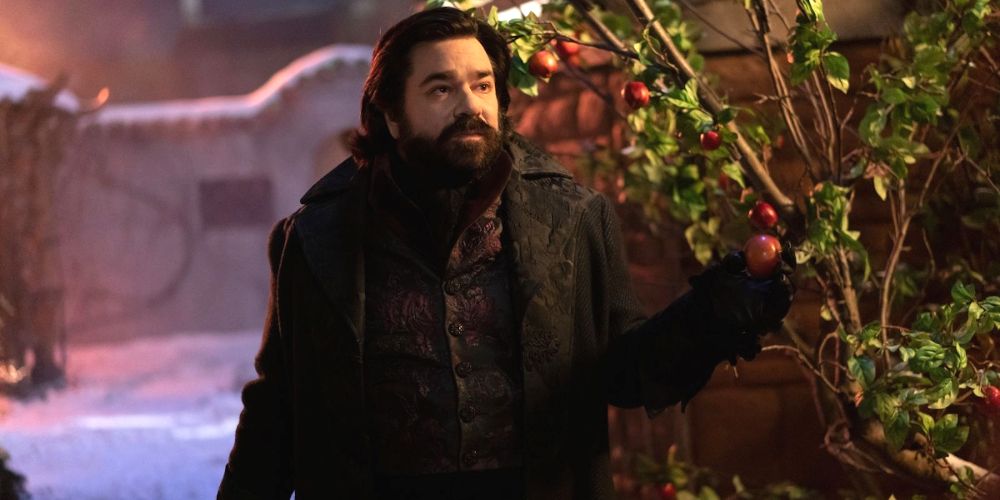 Laszlo holding fruit as he stands in the middle of his garden in What We Do in the Shadows.