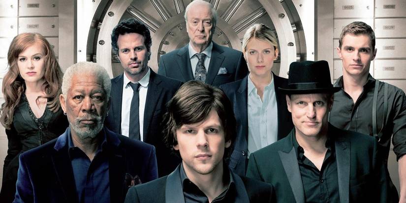 The ensemble cast of Now You See Me posing in front of a bank vault