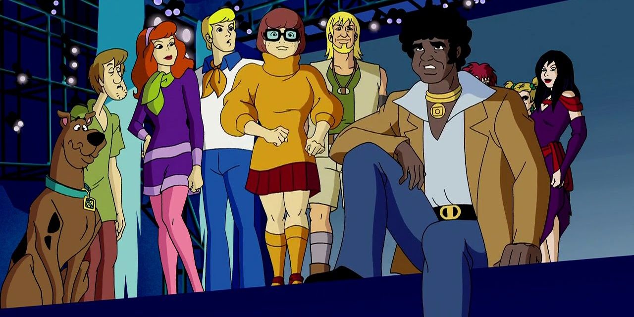 Mystery Inc listens to a legend while standing on stage with the Hex Girls in The Legend Of The Vampire