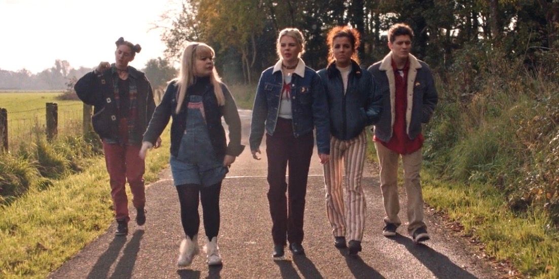 Orla, Clare, Erin, Michelle, and James walk down a secluded road in Derry Girls