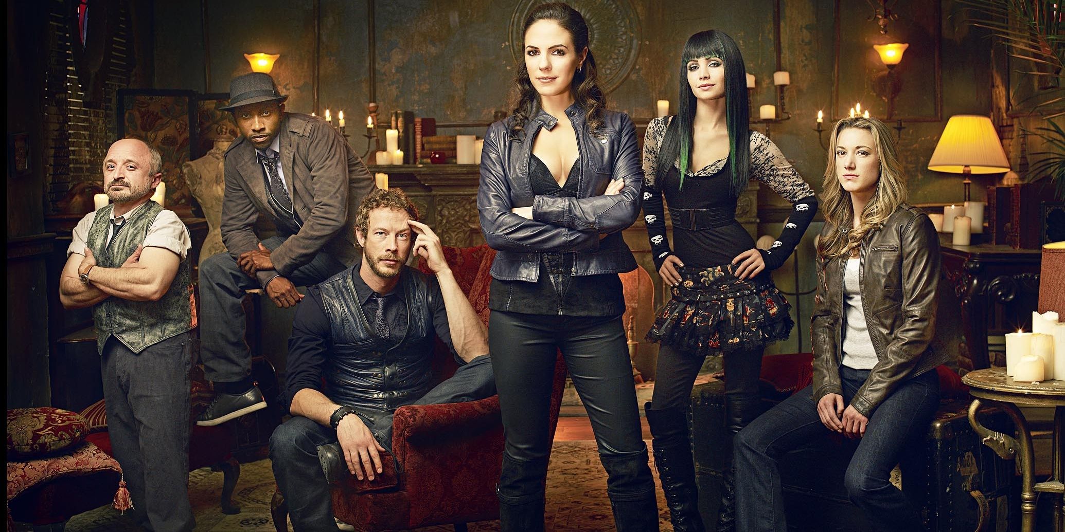 The cast of Lost Girl poses in a gothic lounge for a promotional picture