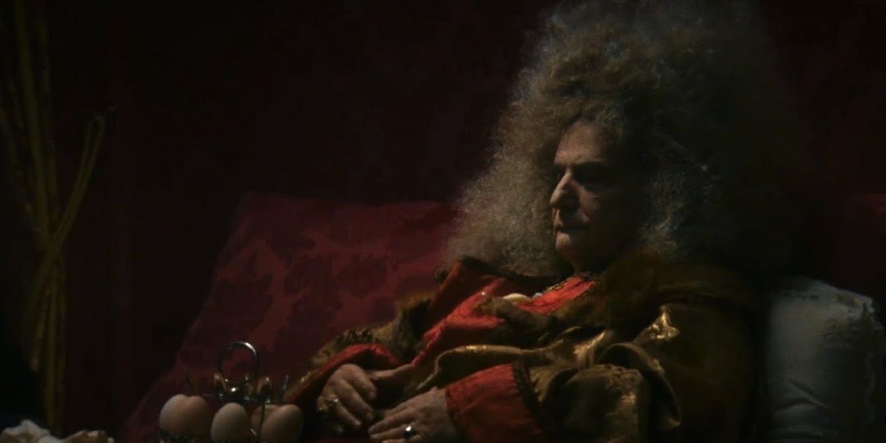 King Louis XIV laying on his bed in a still from The Death of Louis