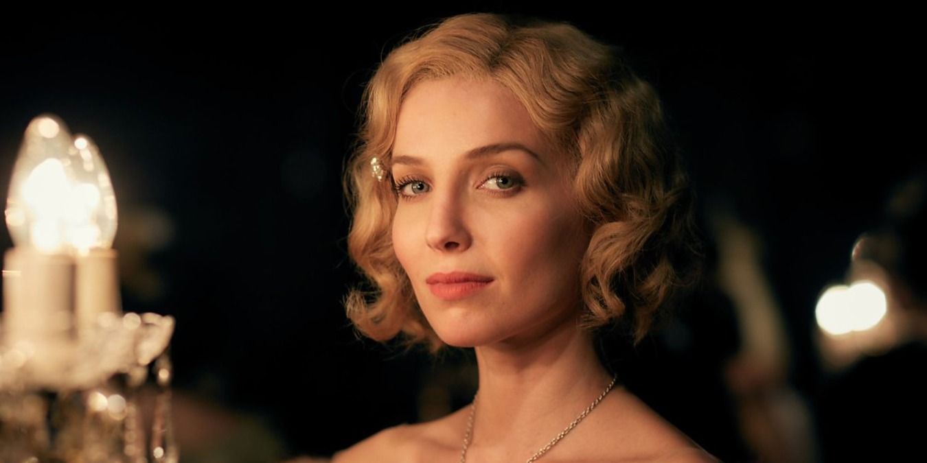 Grace from Peaky Blinders smiles slightly into camera, a light beside her