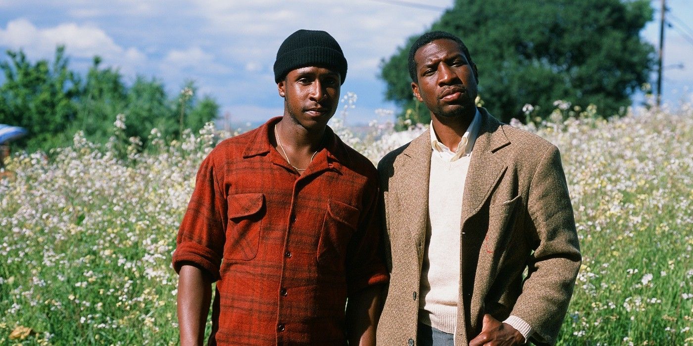 Two black men stand in an open field and look at something