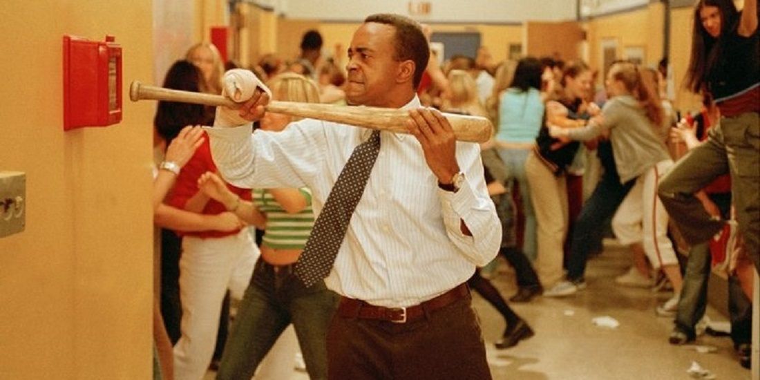 Mr. Duvall uses a bat to hit the fire alarm during the hallway chaos in Mean Girls