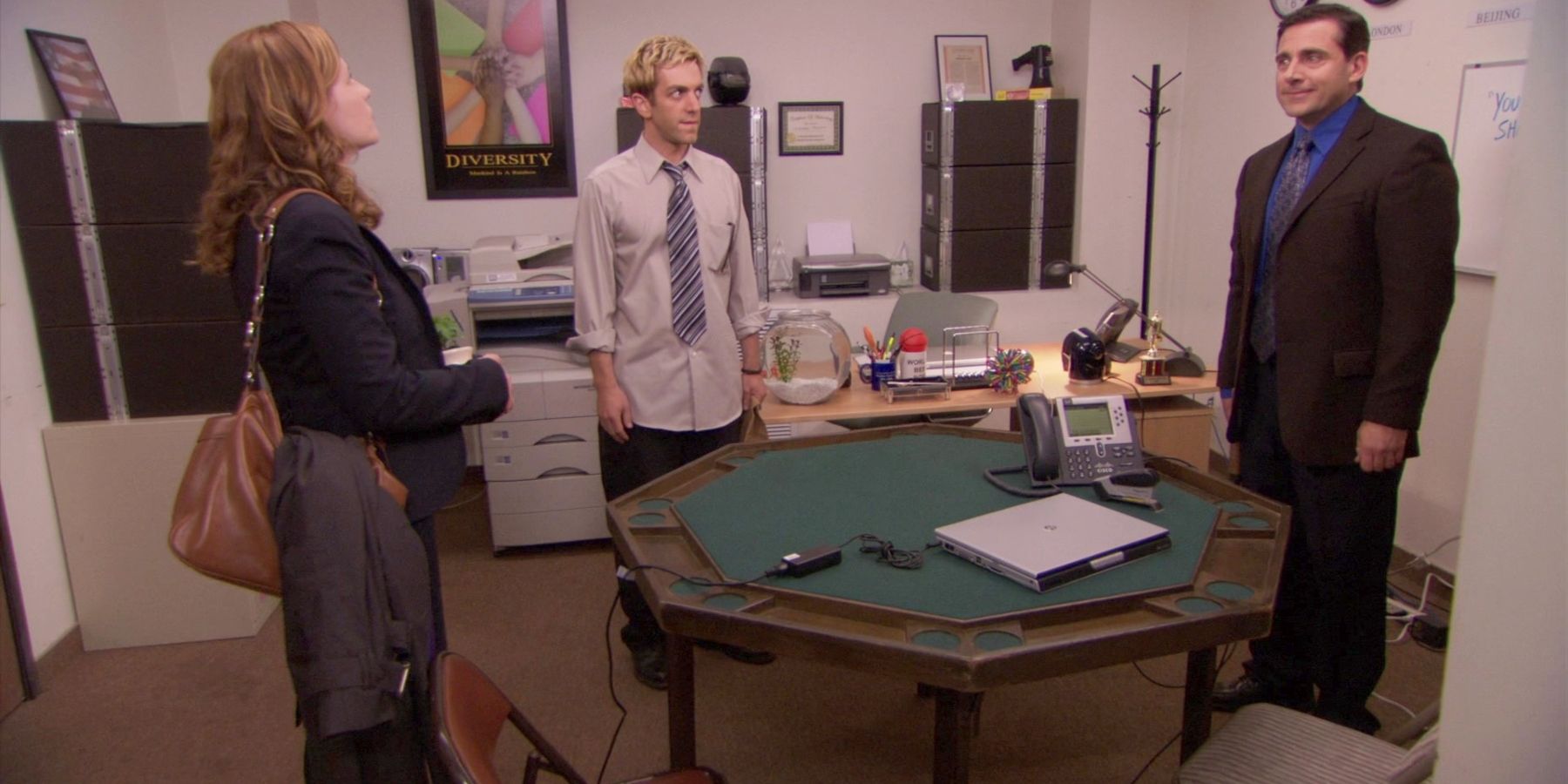 Pam (Jenna Fischer), Ryan (BJ Novak), and Michael (Steve Carell) standing around a table in an office for Michael Scott Paper Company in The Office