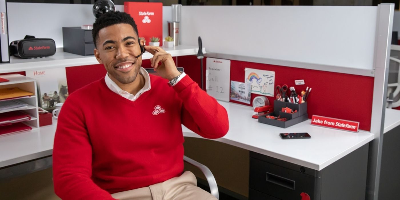 A still of Jake From State Farm smiling at his desk in a commercial.